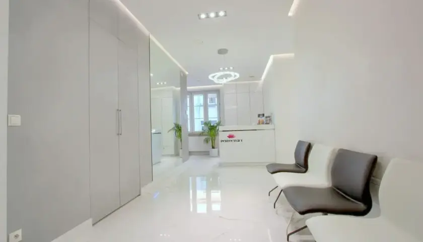 Nowoczesne wnętrze poczekalni kliniki dermatologii estetycznej z recepcją i wygodnymi fotelami.