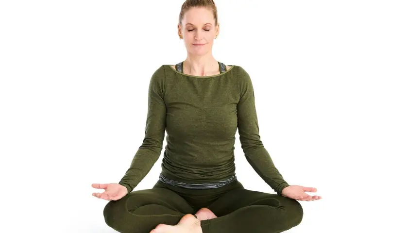 Kvinna i meditationsställning, fokuserad på breath work.