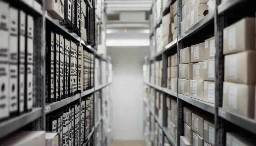 Archiwum pełne segregatorów i pudeł. Wśród nich można znaleźć księgę wieczystą po nr działki, ukrytą gdzieś w tym gąszczu dokumentów.
