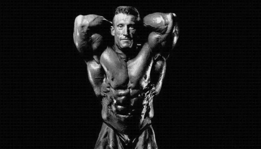 Dorian Yates prezentuje imponującą muskulaturę, dowód ciężkiego treningu.