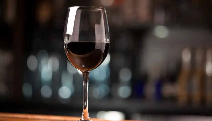 Ein Glas Rotwein, das den vollen Cabernet Sauvignon Geschmack verspricht, steht auf einem Holztisch.