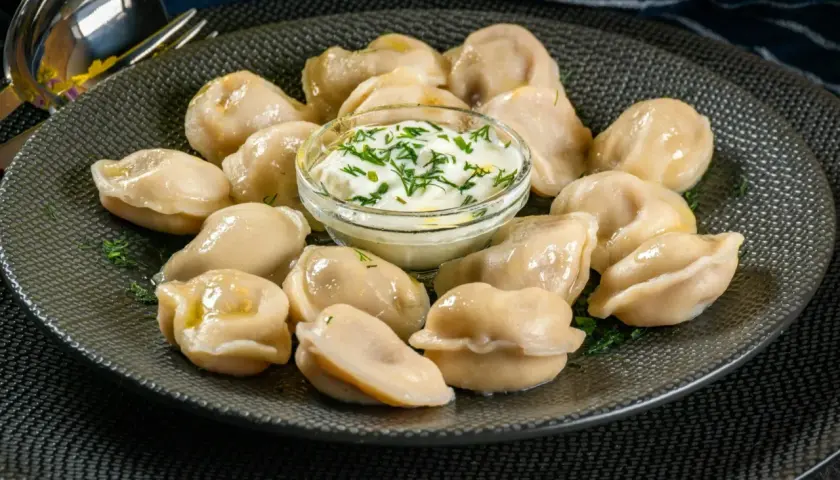 Pyszne pierogi z mięsem z rosołu, podane z gęstą śmietaną i koperkiem. Idealne na obiad.