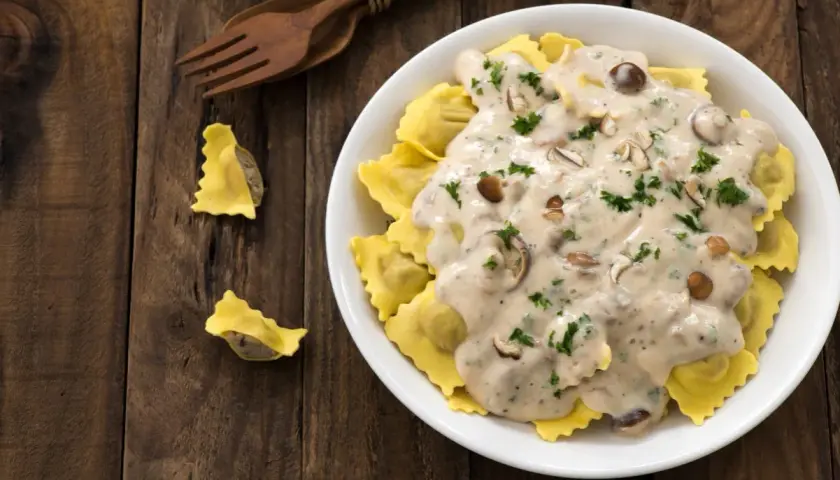 Ravioli z grzybami w sosie śmietana kremówka, posypane natką pietruszki.