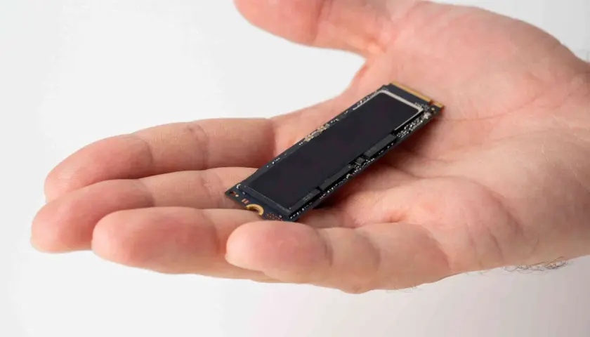 Dłoń trzyma mały dysk SSD M.2. Jego obecność zapewnia szybkie działanie systemu i optymalizację dzięki funkcji ssd trim.