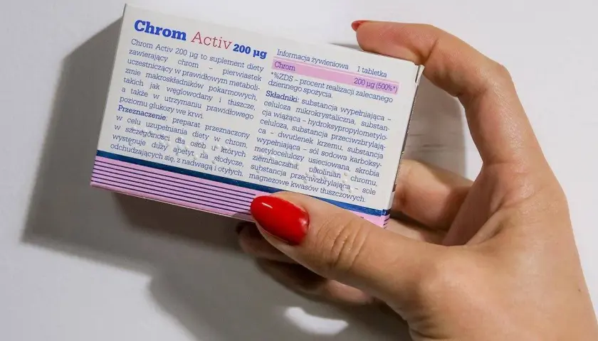 Dłoń trzyma opakowanie suplementu diety Chrom Activ 200 µg, który zawiera chrom.