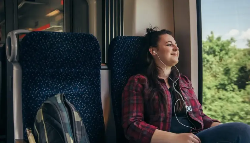 Ung kvinna lyssnar på musik i hörlurar under en resa med biltåg genom Europa.