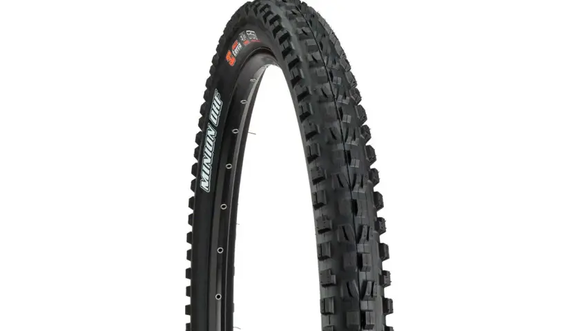 A close-up of a Maxxis Minion DHF tire, ready for a downhill review. Its aggressive tread promises grip.