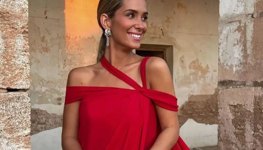 María Pombo, radiante con un vestido rojo, sonríe mientras posa. Su edad se refleja en su energía y estilo.