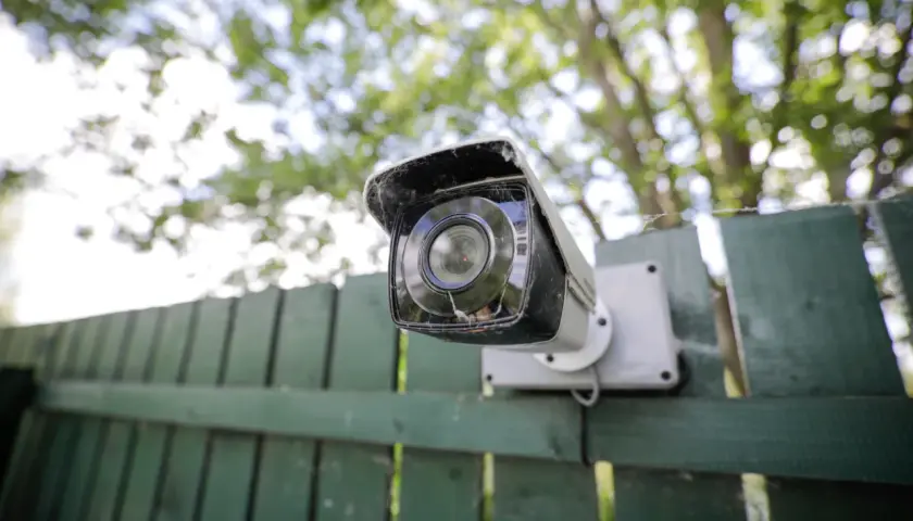 Cámara de seguridad montada en una valla verde. Ideas de camuflaje para ocultar cámaras.