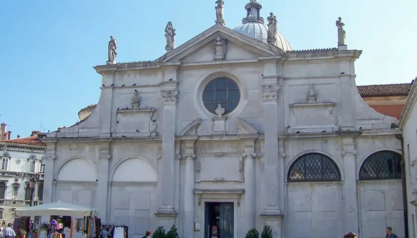 Façade de Santa Maria Formosa à Venise, avec des statues, un dôme et une place animée.