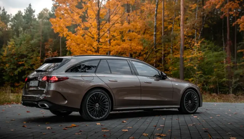 Brązowy Mercedes E300de kombi na tle jesiennego lasu.