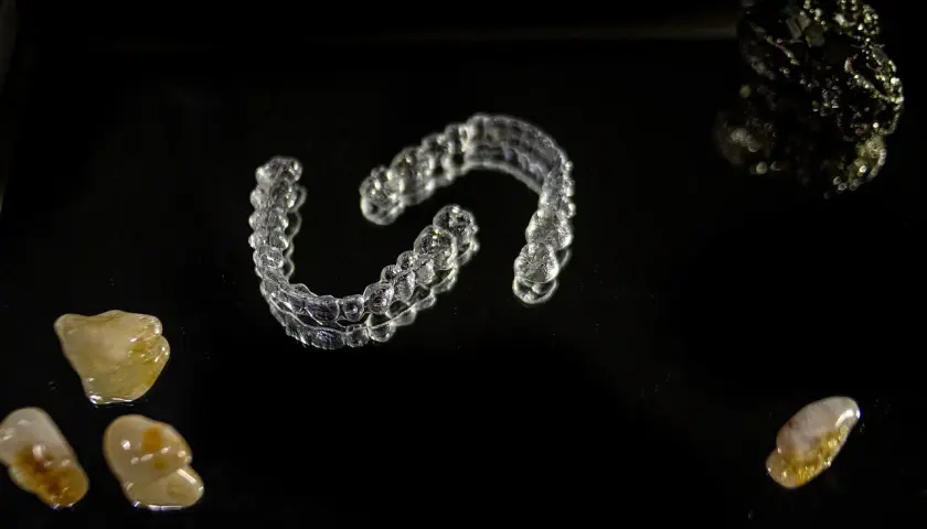 Przezroczyste nakładki Invisalign vs tradycyjny aparat ortodontyczny. Kamienie i kryształy na czarnym tle.