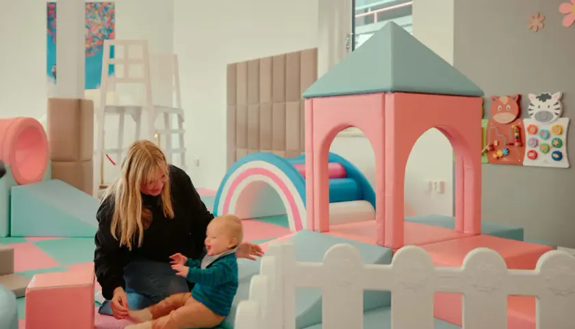 En mamma leker med sitt barn i en lekplats. En rolig och gratis upplevelse för barn i Stockholm.