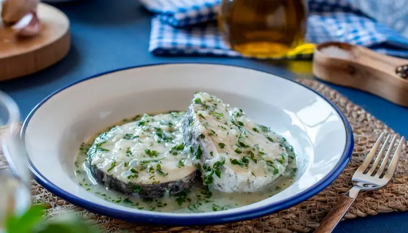 Dos rodajas de merluza en salsa verde, con perejil picado y un toque de ajo.