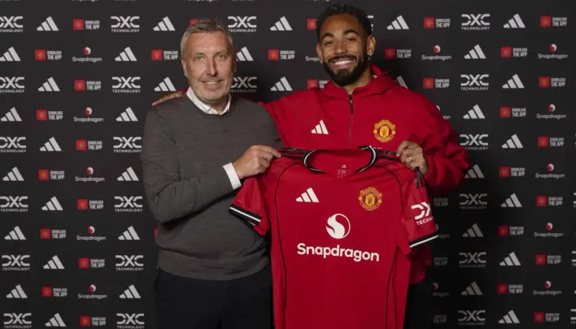 Dwóch mężczyzn prezentuje czerwoną koszulkę Manchester United. To ważny moment w kontekście manchester united transfery.