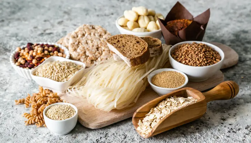 Różnorodne produkty zbożowe i strączkowe: ryż, kasza, makaron, chleb, płatki owsiane, fasola.