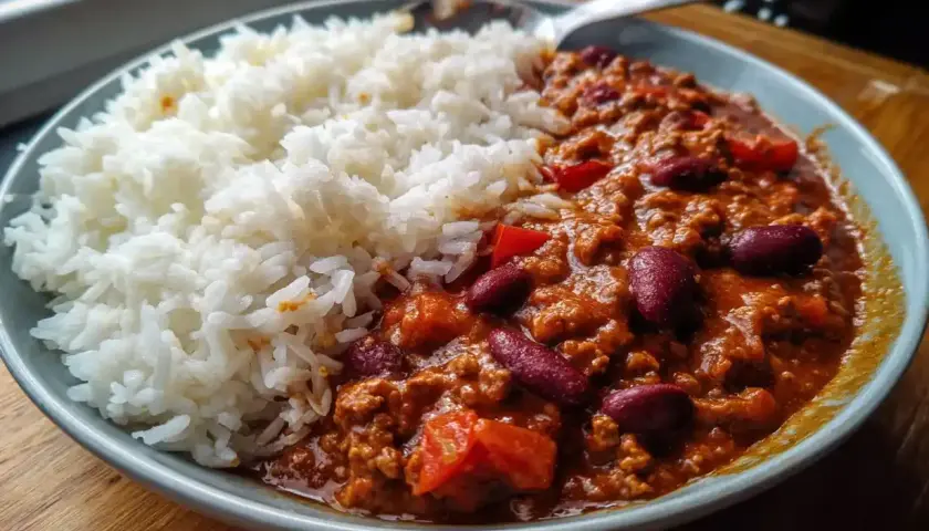En skål med fluffigt ris bredvid en mustig chili con carne med bönor och köttfärs. En perfekt middag!