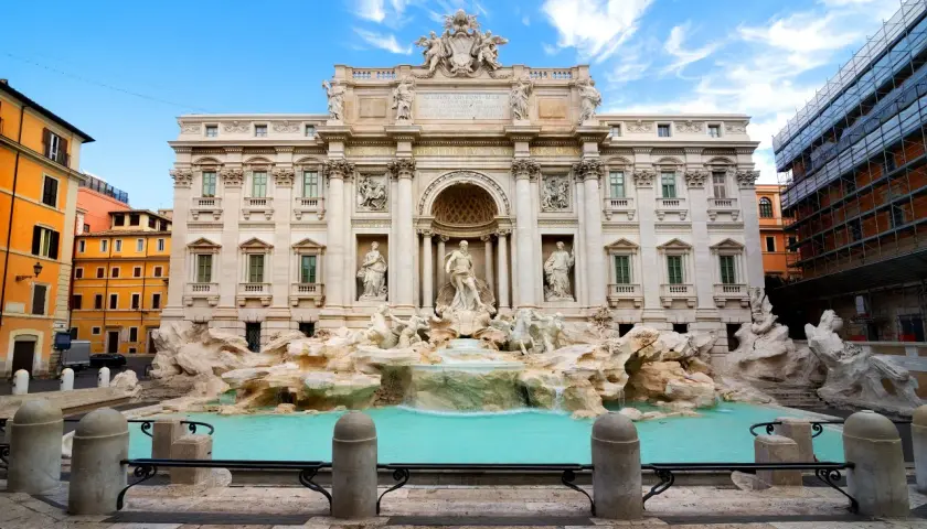 La Fontana di Trevi, con le sue sculture barocche e l'acqua turchese, incanta sotto un cielo azzurro.