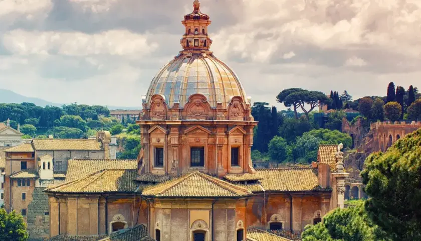 Cupola della chiesa dei Santi Luca e Martina a Roma, con tetti e alberi circostanti sotto un cielo nuvoloso.