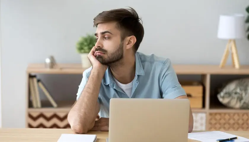 Homme ennuyé devant son ordinateur, illustrant la sédentarité. Il s'ennuie, signe de sédentarité.