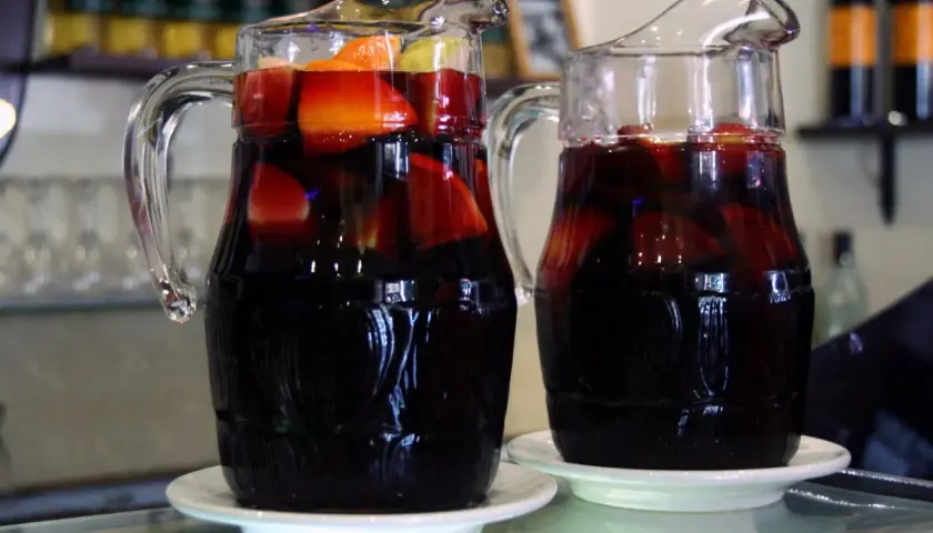 Dwa dzbanki z ciemnym napojem i owocami, idealne na lato. Przepis na tinto de verano.