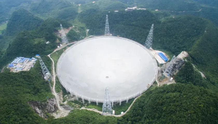Największy radioteleskop na świecie, FAST, w otoczeniu zielonych wzgórz. Jego ogromna czasza odbiera sygnały z kosmosu.