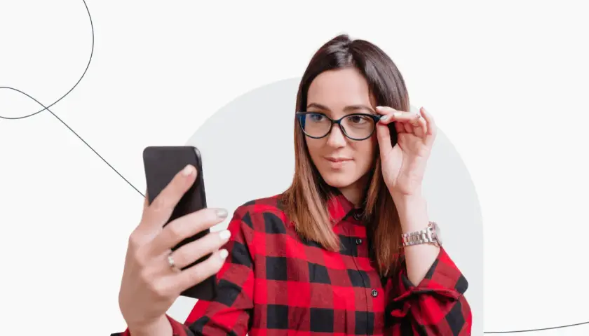 Kobieta w okularach robi selfie telefonem, zastanawiając się, czy do dowodu można mieć zdjęcie w okularach.