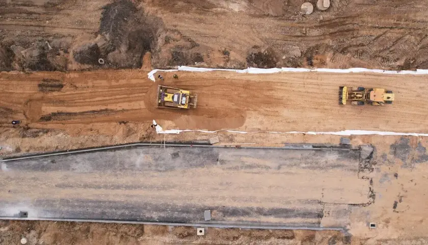 Bagger verdichten die **hydraulisch gebundene Tragschicht** auf einer Baustelle.
