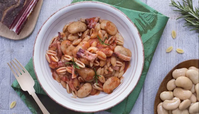 Gnocchetti alla sarda con fagioloni, pancetta y salsa de tomate, decorado con romero.