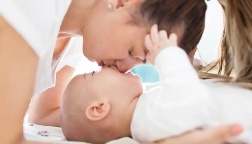 Ciepły uścisk mamy i jej 7 miesięczne dziecko. Delikatne pocałunki i miłość w spojrzeniu.
