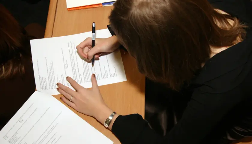 Kobieta pisze na kartce, ucząc się, jak zostać rzeczoznawcą majątkowym.