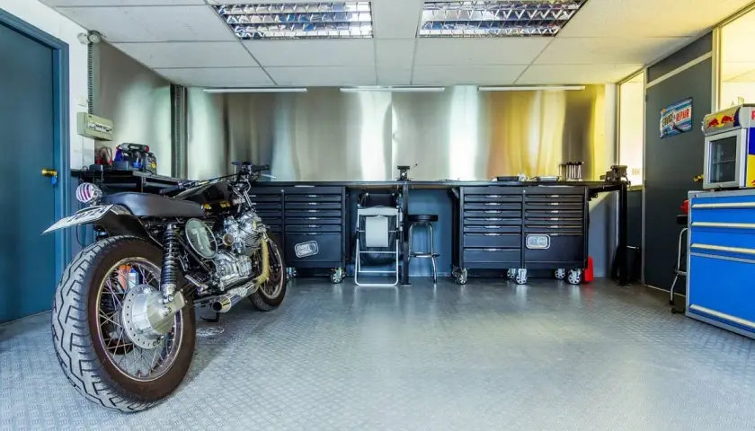 Garage per moto fai da te con moto custom, banchi da lavoro, cassettiere e attrezzi.