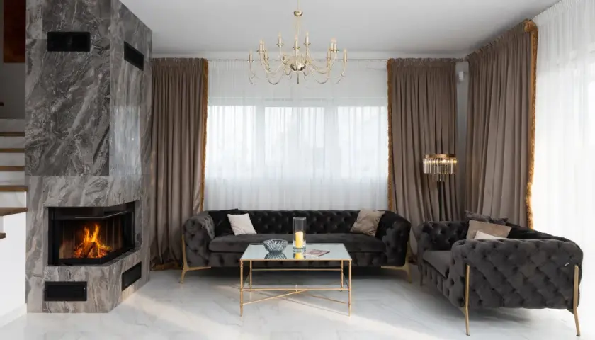 Eleganckie atrapa kominka z marmuru, nowoczesne aranżacje salonu z pikowanymi sofami i złotymi dodatkami.