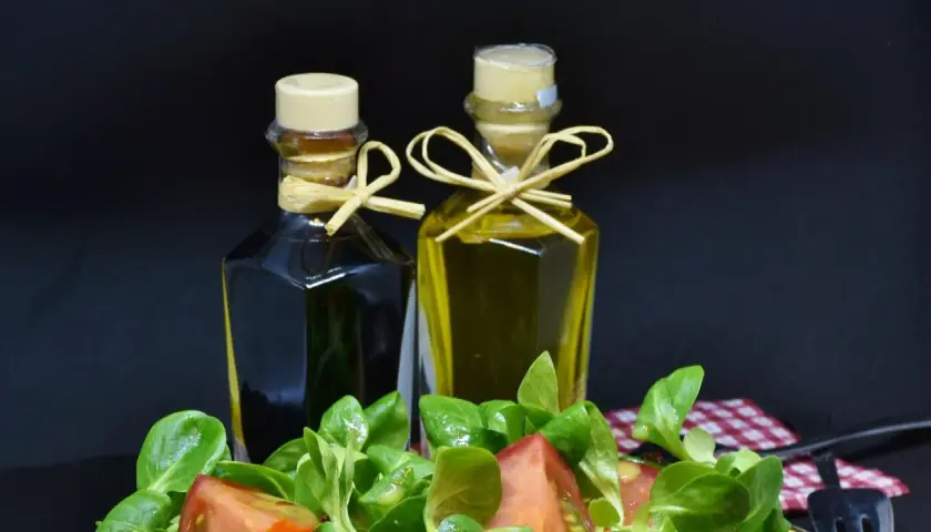 Zwei Flaschen Öl und Essig, daneben ein Salat. Wenn du zu viel Essig hast, was tun? Weniger nehmen!