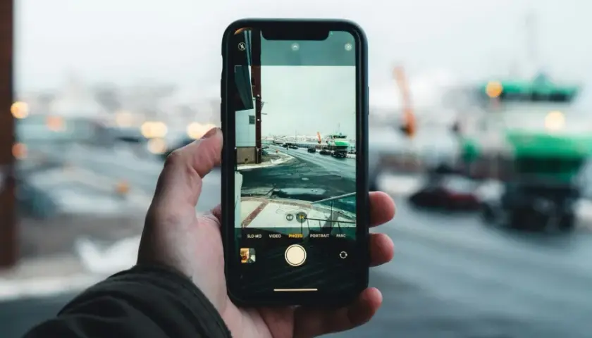 Dłoń trzyma smartfon, na ekranie którego widać zimowy krajobraz portu. Zbliżenie uchwyciło subtelny pixel shift, dodając głębi scenie.