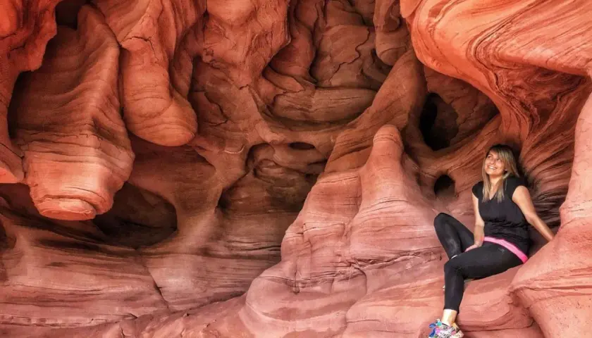 Una mujer sonríe sentada en las impresionantes formaciones rocosas de las coves de Can Riera, un paisaje natural de arenisca erosionada.