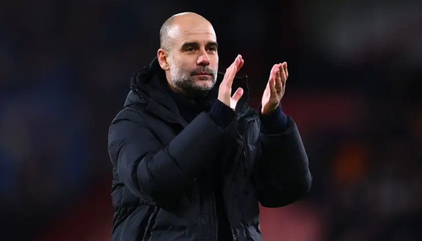 Pep Guardiola, znany z tego, że prowadzone drużyny osiągają sukcesy, klaszcze na boisku w zimowej kurtce.