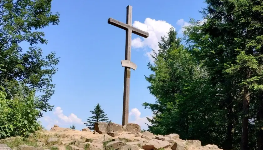 Drewniany krzyż na skalistym szczycie, otoczony zielenią. Idealne miejsce, by odkryć, co zobaczyć w Górach Świętokrzyskich.
