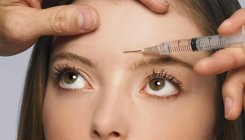 Nahaufnahme einer Frau, der Botox in die Stirn injiziert wird. Mögliche botox spätfolgen im Blick.