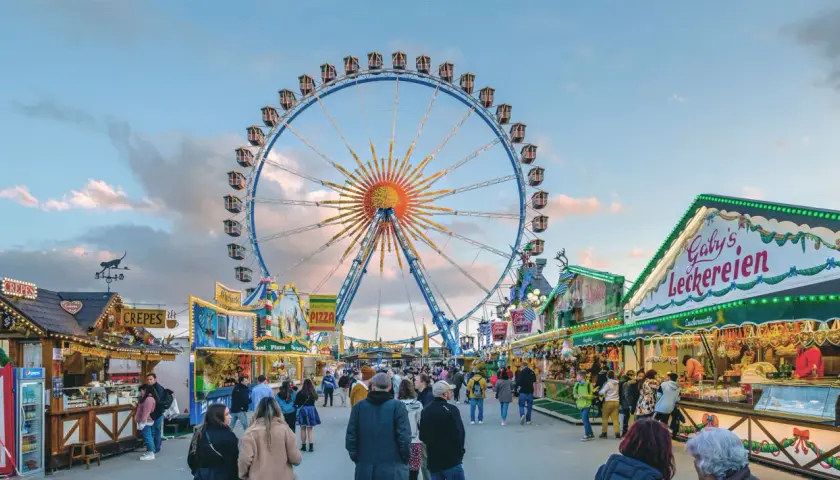 Buntes Treiben auf dem Frühlingsfest München mit Riesenrad, Essensständen und vielen Besuchern.