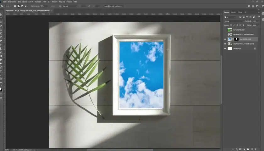 Ein Photoshop-Mockup mit einem weißen Rahmen, der einen blauen Himmel zeigt, daneben ein grünes Blatt.