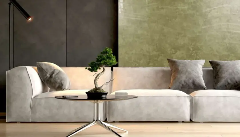Nowoczesny salon z sofą, stolikiem i bonsai. Ściana za sofą pokryta jest efektowną **glinką wenecką** w odcieniach zieleni i grafitu.