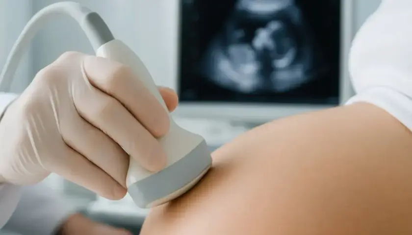 Ginekolog wykonuje USG. Na ekranie widać zarodek, to **6 tydzień ciąży**.