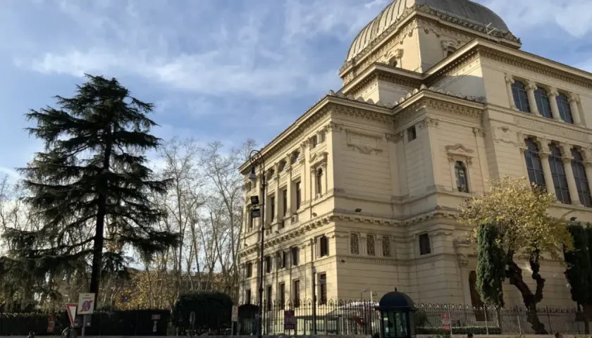 Grande Sinagoga e alberi nel quartiere ebraico di Roma, sotto un cielo azzurro con nuvole.