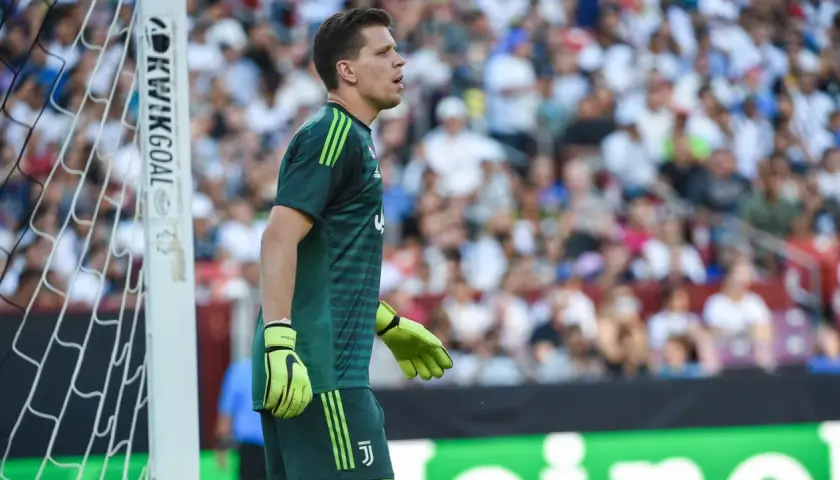 Wojciech Szczęsny w zielonej koszulce bramkarskiej Juventusu stoi przy bramce.