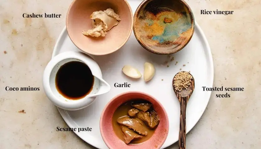 Ingredients for a delicious sesame sauce for hot pot: cashew butter, coco aminos, sesame paste, garlic, rice vinegar, and toasted sesame seeds.