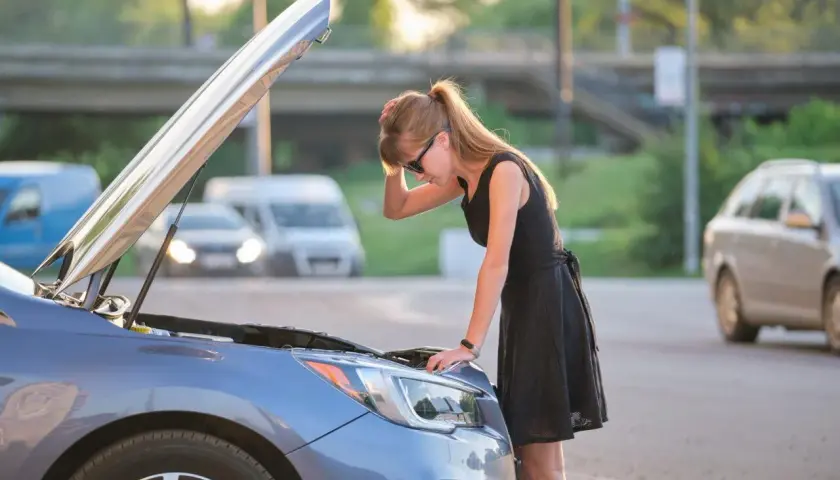 Donna preoccupata guarda il motore della sua auto, il motore diesel gira ma non parte.