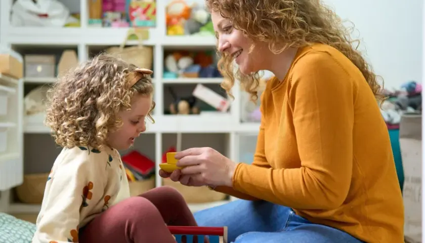 Mama z córką bawią się w pokoju pełnym zabawek. Czy urlop wychowawczy wlicza się do stażu pracy? To pytanie nurtuje wiele mam.