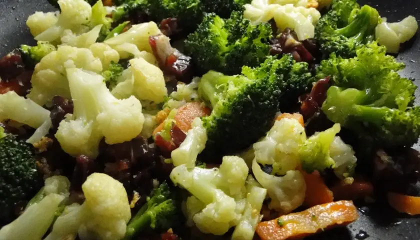 Un panache de verduras salteadas en sartén, con brócoli, coliflor y zanahoria, listo para disfrutar.