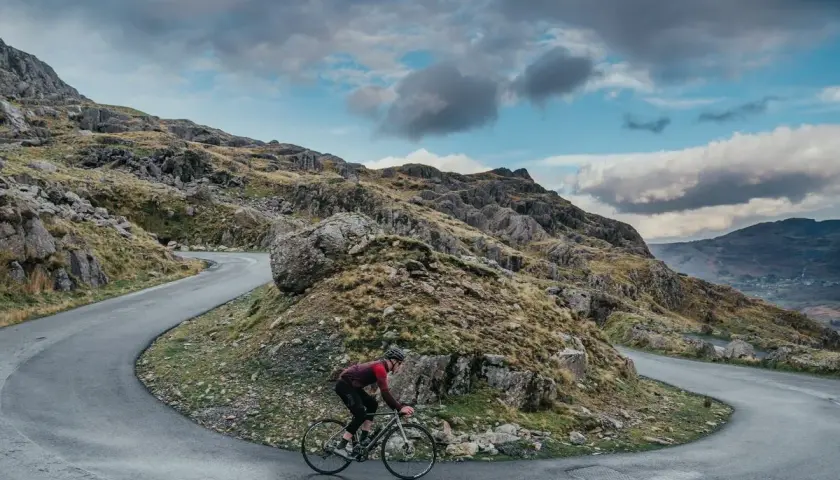 Ciclista en una carretera sinuosa en un paisaje montañoso, disfrutando de su aventura de España en bicicleta.